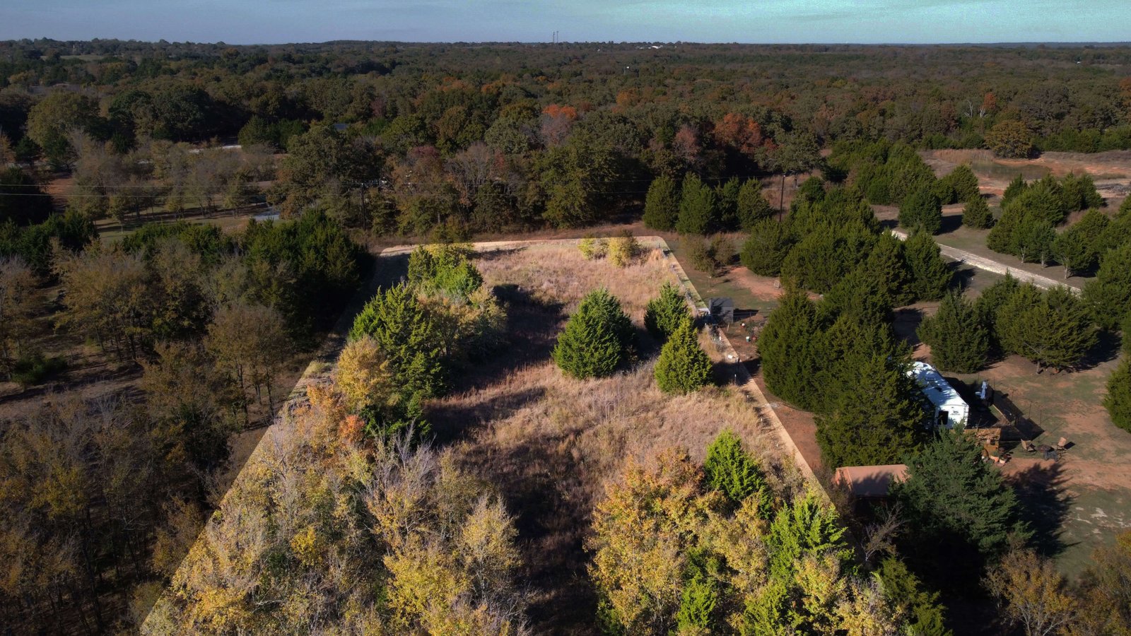 Shaded aerial view of the rear portion of a wooded 1-acre lot near Lake Texoma in Gordonville, Texas with mixed tree coverage and open space.