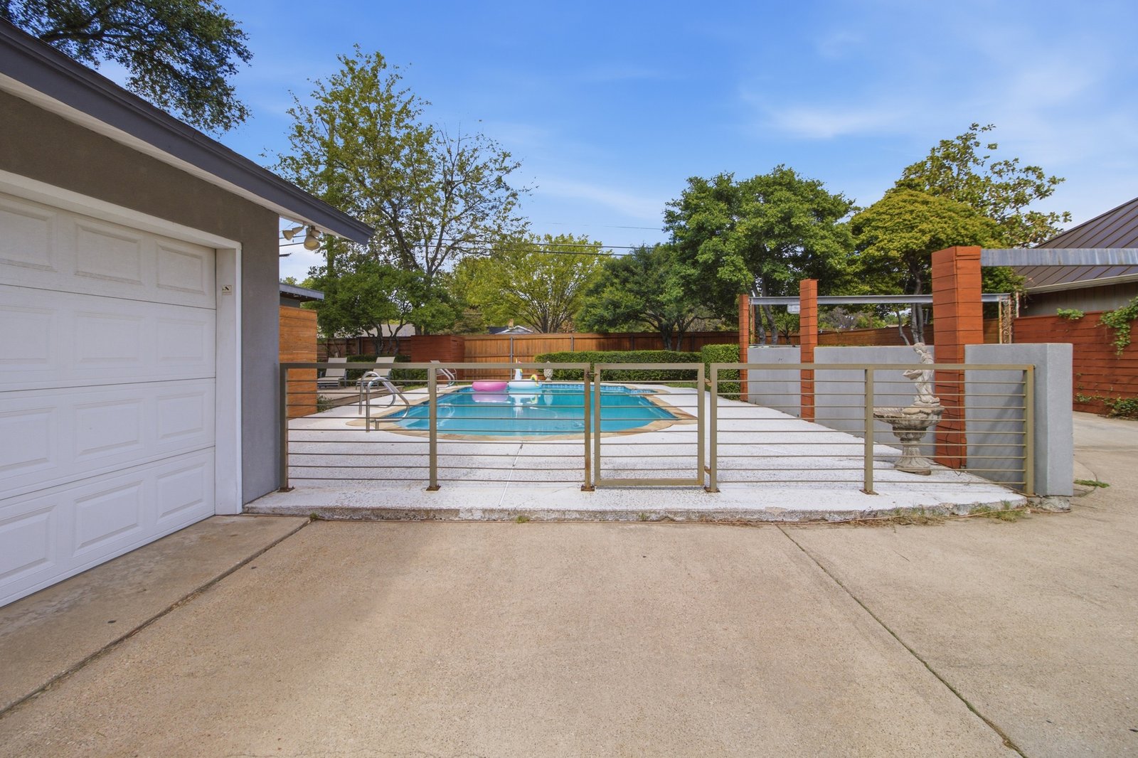 54_img_0173 Step through the decorative metal gate into your own backyard retreat! The fenced pool area is thoughtfully separated from the driveway and additional parking, creating a distinct space for relaxation and entertaining. Beyond the gate, the sparkling swimming pool, expansive decking, and mature landscaping set the stage for everything from quiet afternoons in the sun to lively gatherings with friends.
