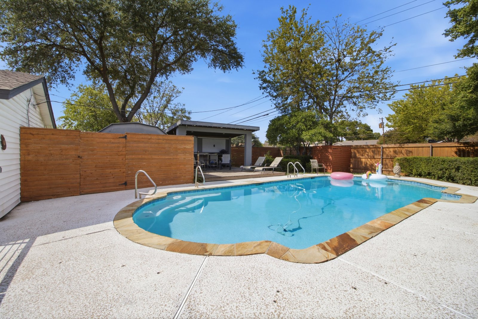 55_img_0191 Your own backyard retreat! The sparkling in-ground pool takes center stage, surrounded by an expansive deck with plenty of room for lounging and entertaining. Just steps away, the covered cabana offers a shaded gathering space, while the wood privacy fencing and mature trees create an inviting outdoor setting. A dedicated fenced enclosure discreetly separates the pool equipment from the entertaining areas.