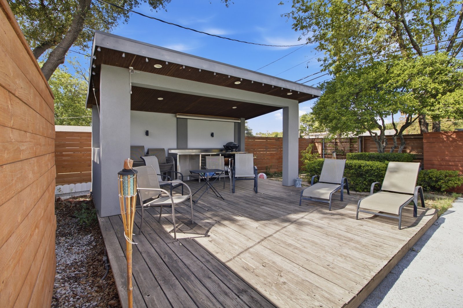 58_img_0212 Take outdoor living to the next level with this spacious poolside cabana and expansive wood deck. The covered gathering area features a rich wood-paneled ceiling, recessed lighting, and decorative string lights that help set the mood for evening gatherings. With room for dining, conversation, and poolside lounging, this versatile space is equally suited for intimate get-togethers or lively celebrations. The adjacent open deck provides additional space to enjoy the sunshine just steps from the pool.