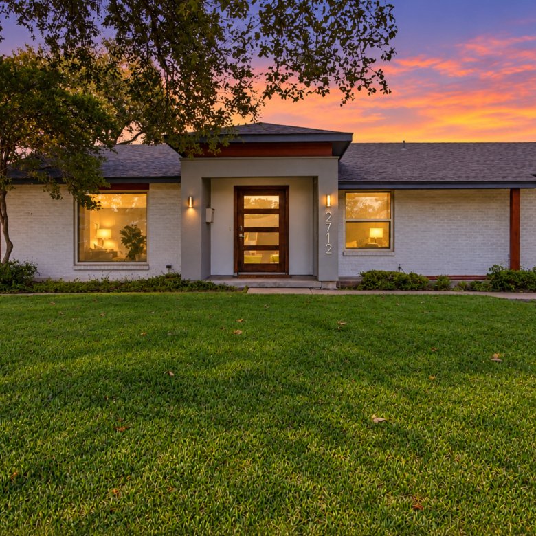 Welcome to 2712 Beechmont Place, where contemporary updates and mid-century modern influences meet the charm of an established neighborhood. A white brick exterior, distinctive modern entryway, and warm architectural lighting create an inviting first impression. Mature trees, an expansive front lawn, and thoughtfully arranged landscaping complement the home's clean lines and attractive single-story design.
